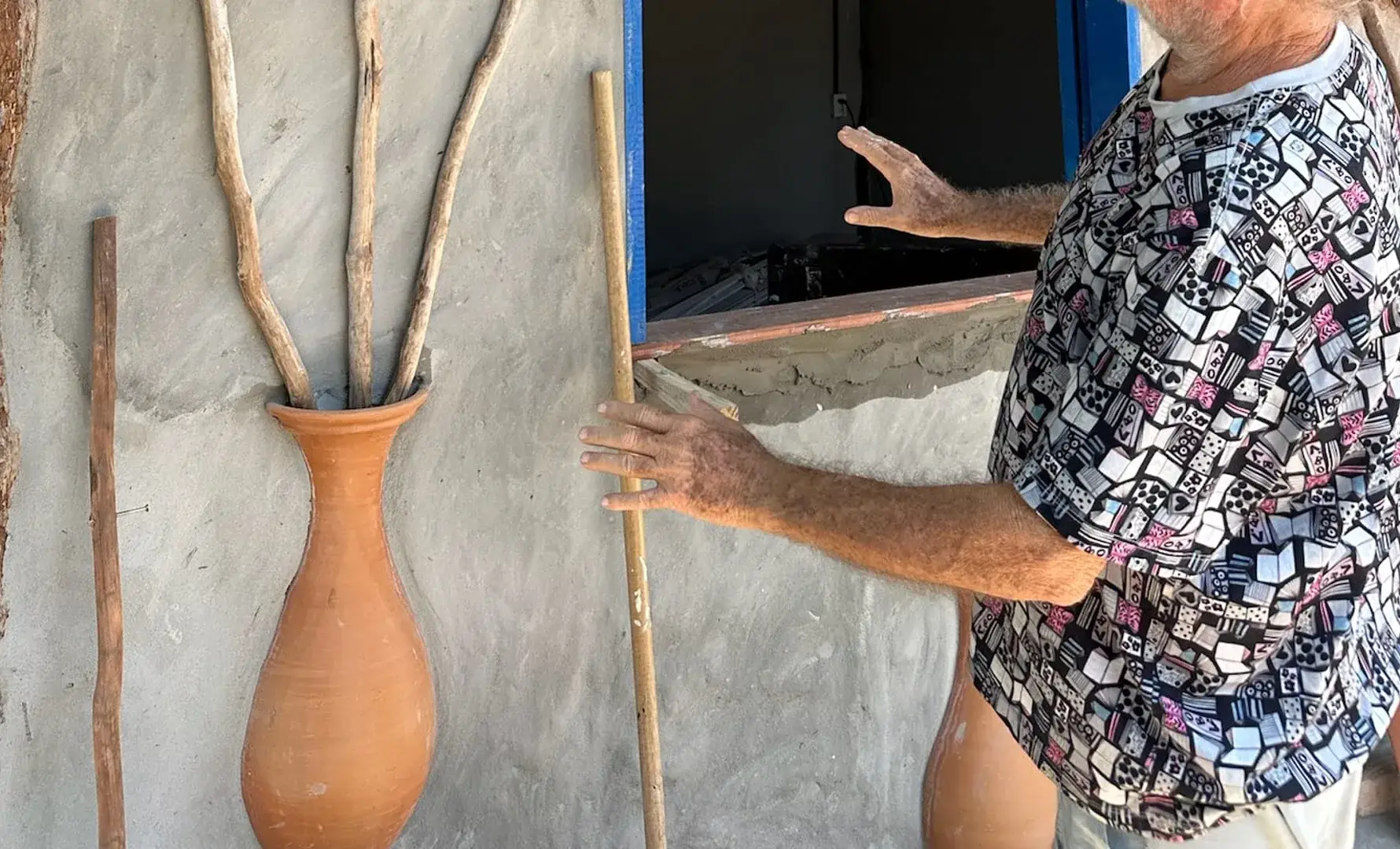 Buna ao lado de uma parede com um vaso de barro embutido e galhos de madeira