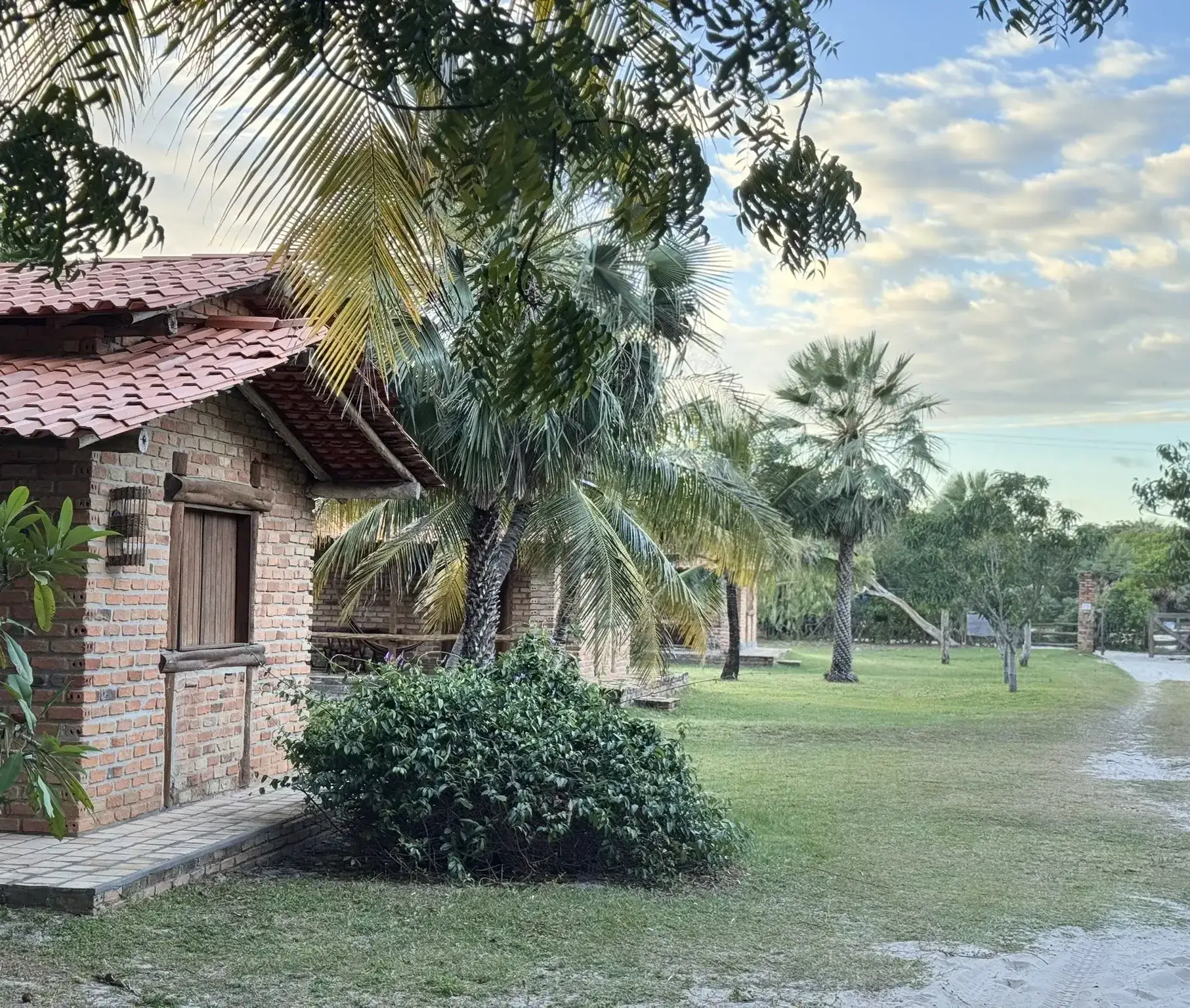Bungalow de tijolo do Rancho do Buna entre árvores e coqueiros