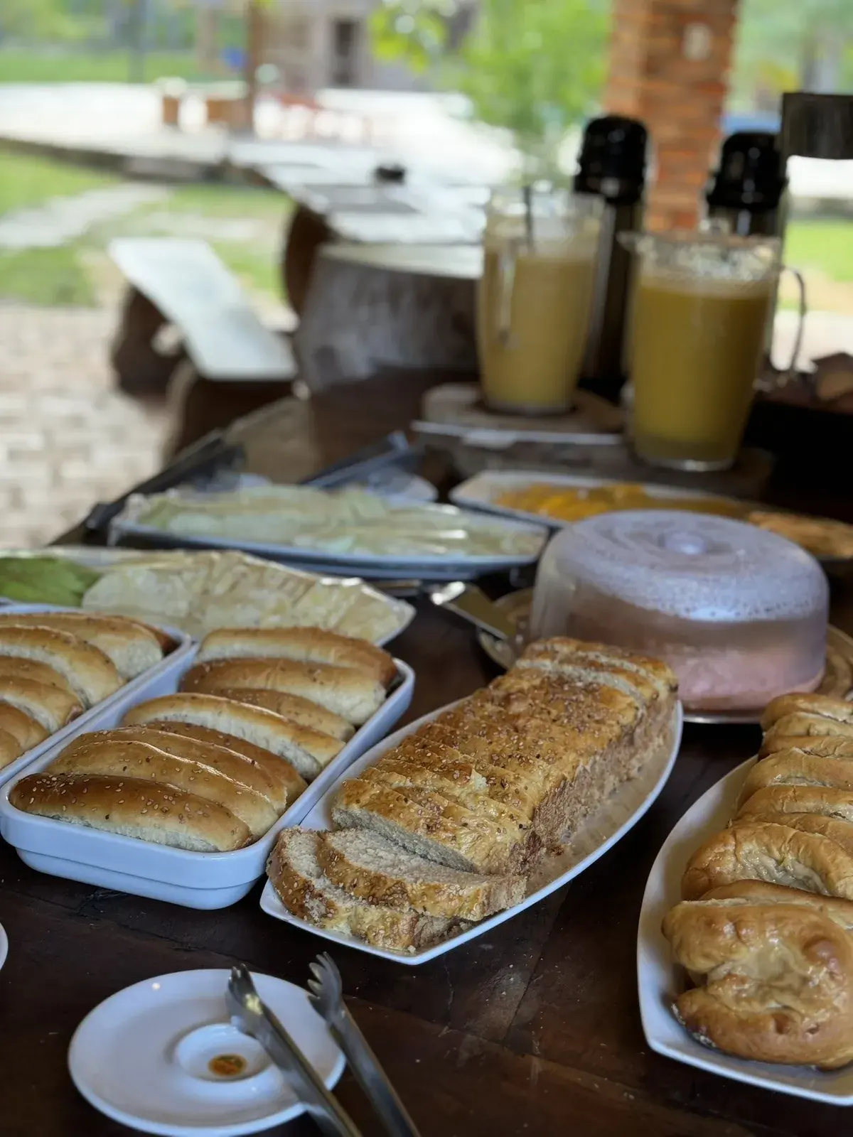 Pães caseiros, bolo e jarras de suco na mesa do café da manhã
