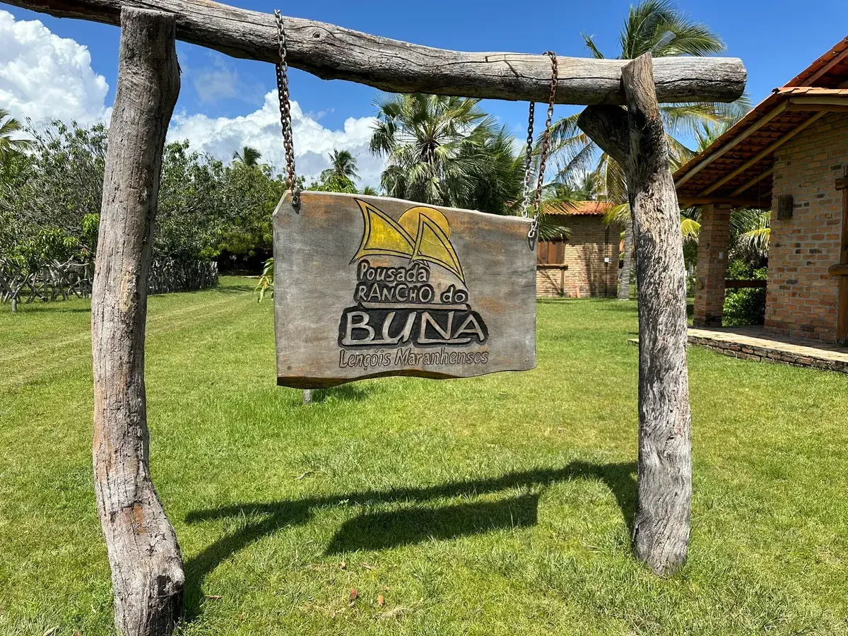 A placa entalhada da Pousada Rancho do Buna, pendurada num pórtico de troncos na entrada