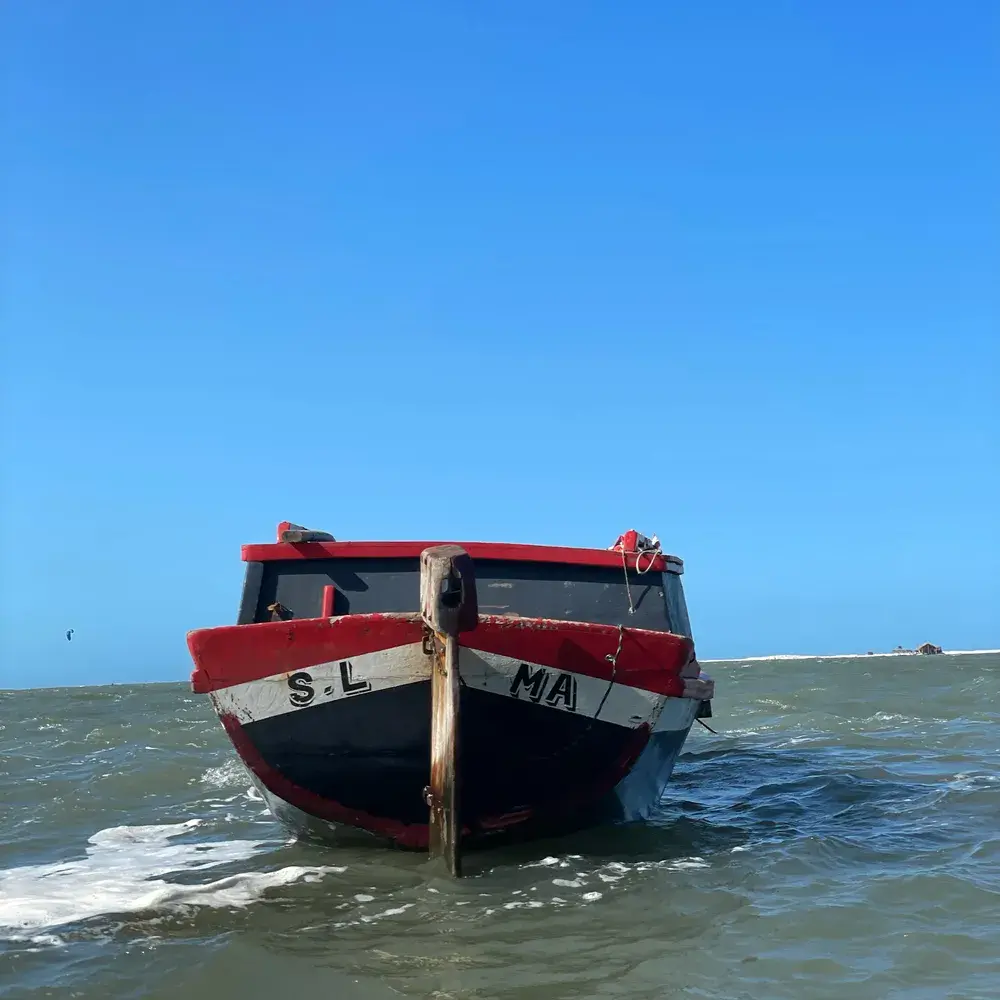 A proa de um barco de madeira vermelho e preto, parado na água